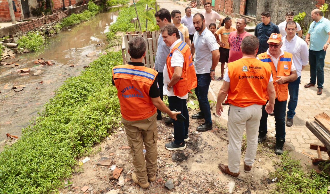 prefeito evandro observa um canal, acompanhado de assessores